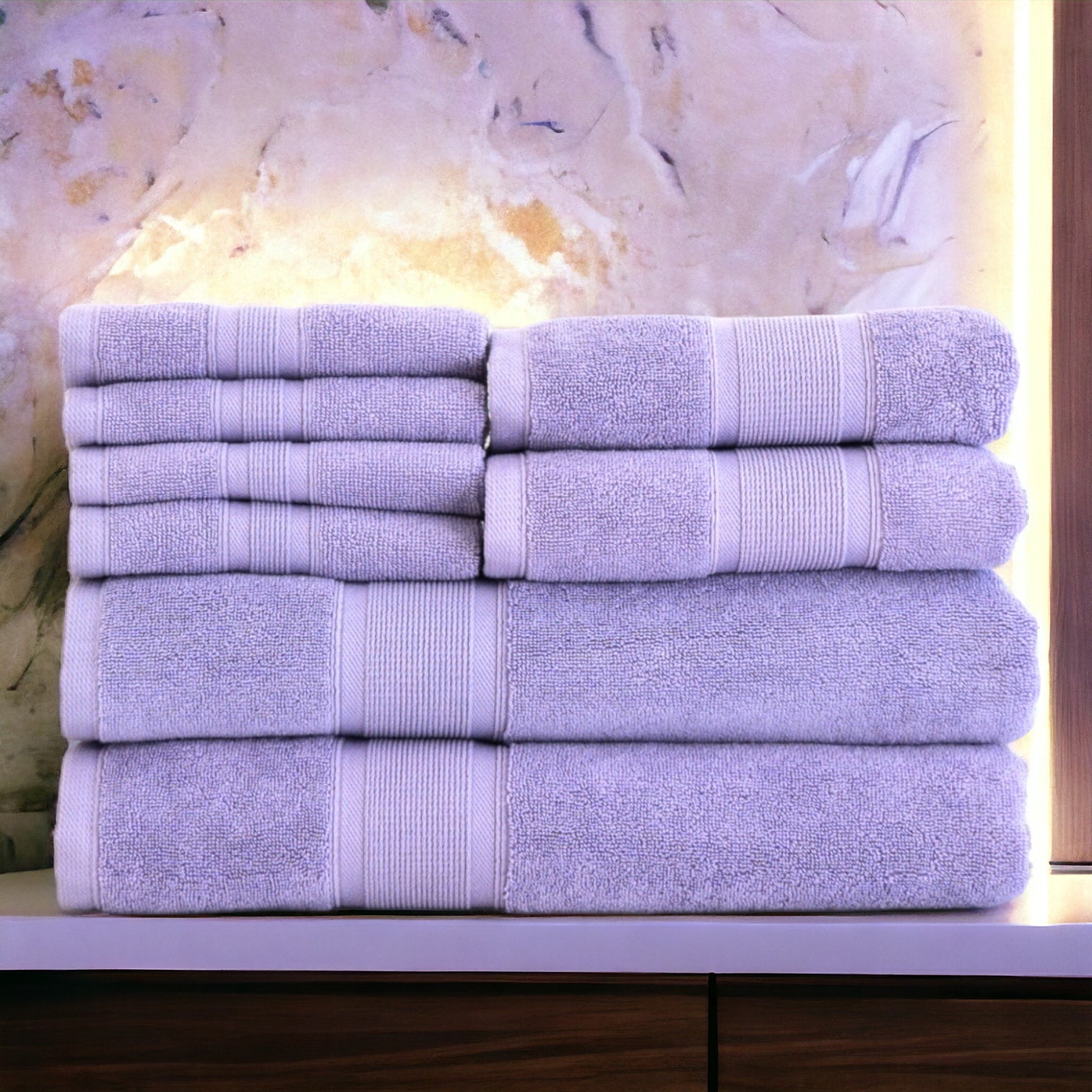 Stack of purple towels on a marble surface with a warm light in the background