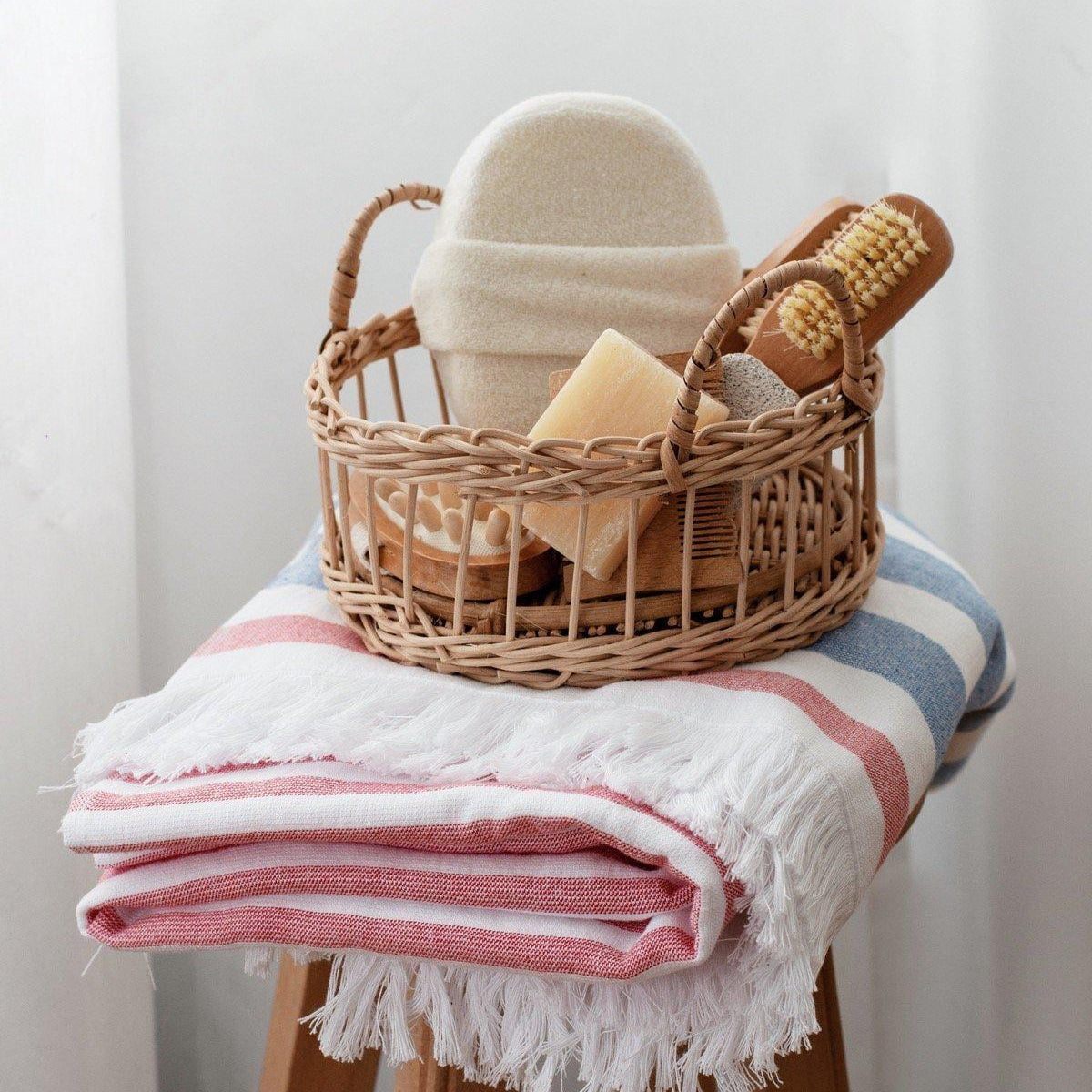 Luzia Peshtemal Beach and Pool Towel in Blue and Red Shown with Personal Care Products