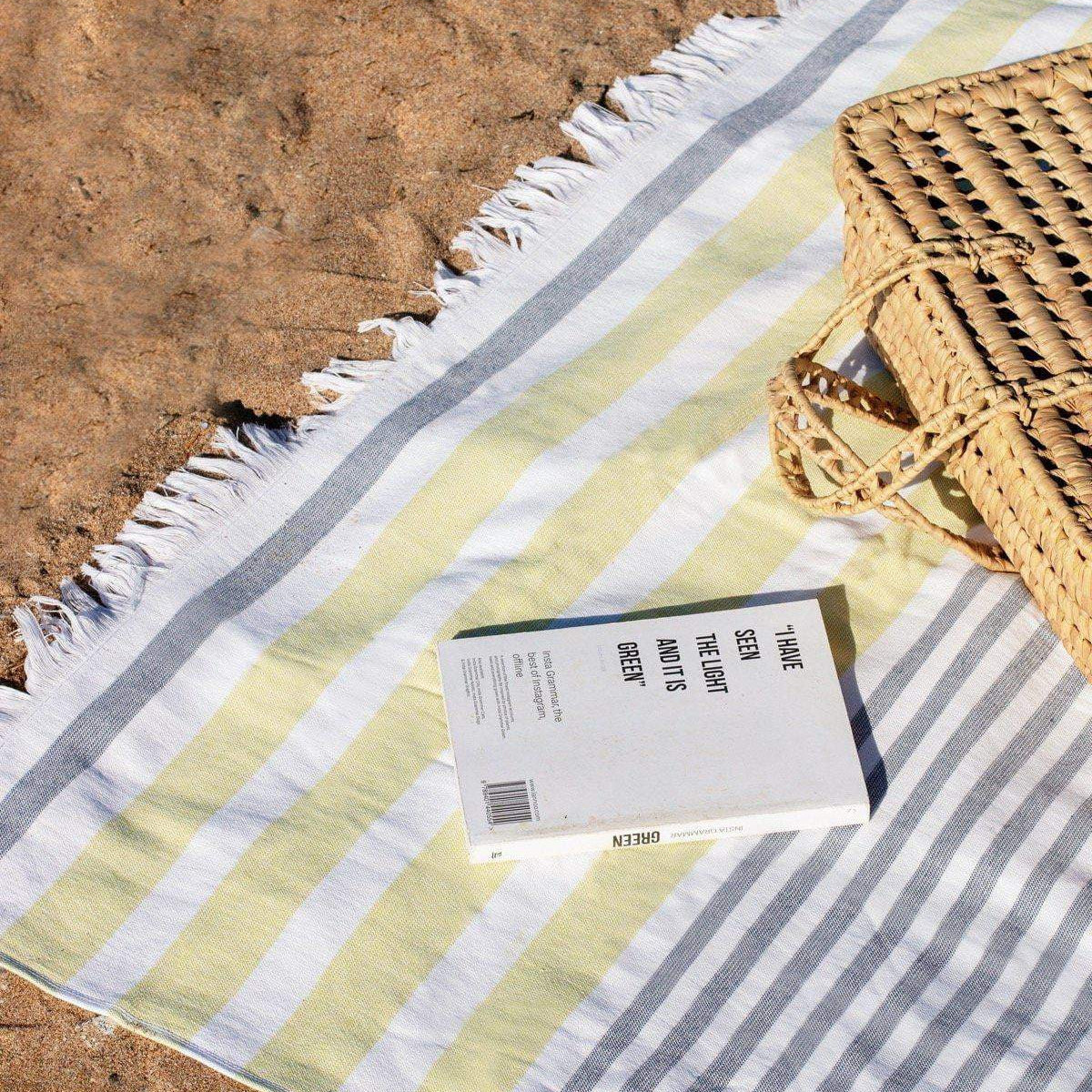 Luzia Peshtemal Beach and Pool Towel in Yellow and Grey on the Beach with Book